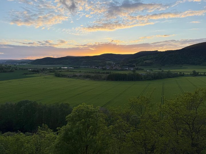 Das Saaletal im Abendlicht, darunter Felder und das Dorf Weißen