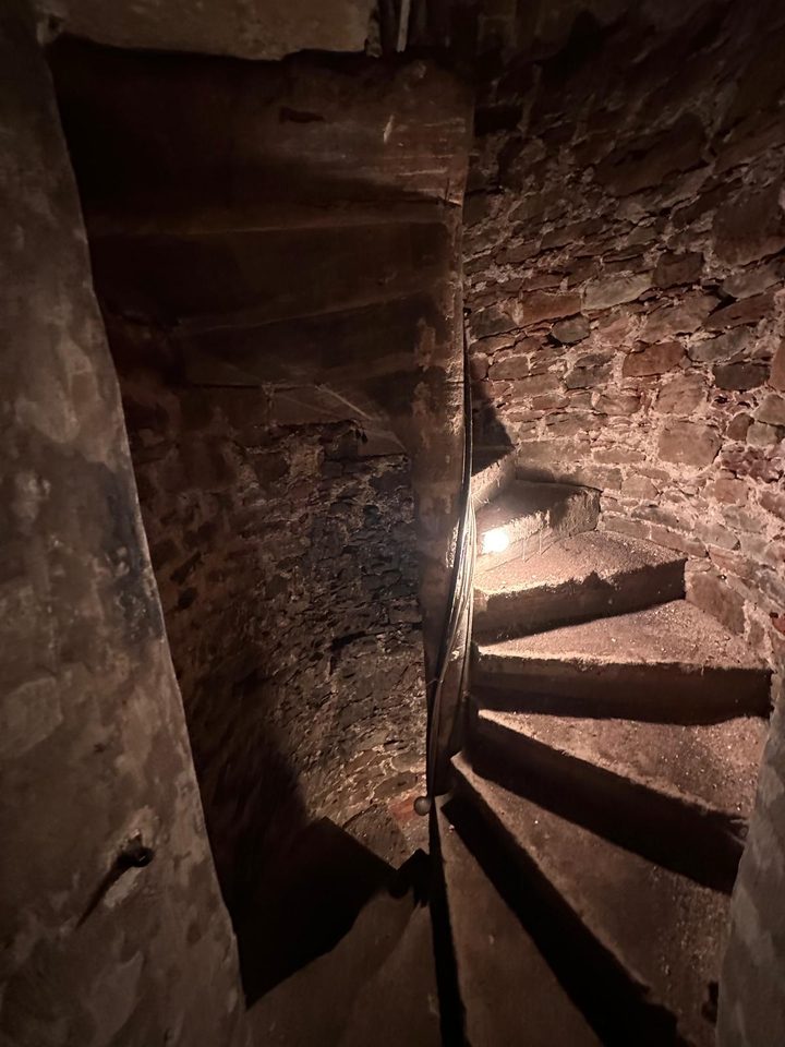 Enge Wendeltreppe aus Sandstein im Turm, nur von einer Lampe beleuchtet
